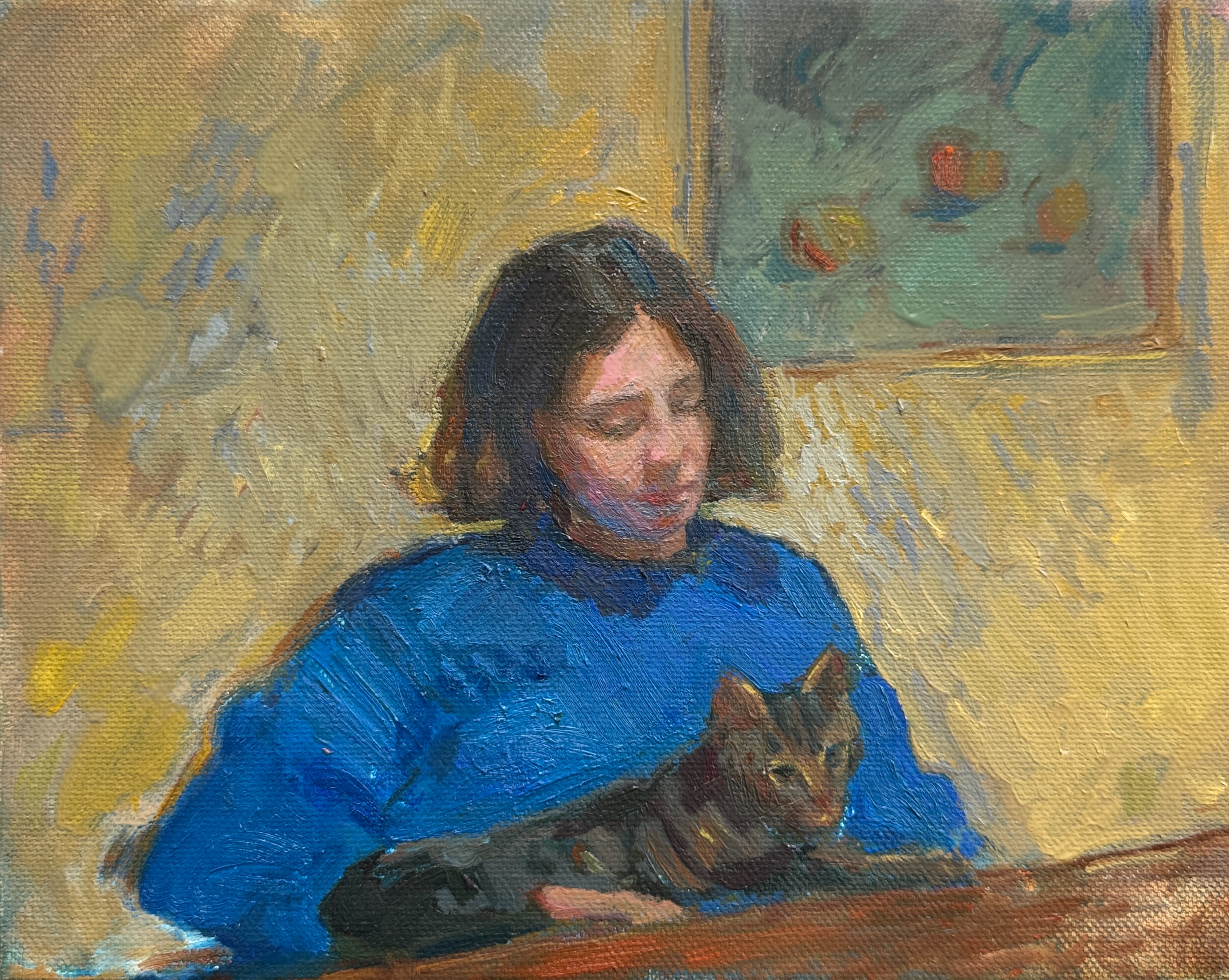 A woman sat at a table with a cat lying across her lap.